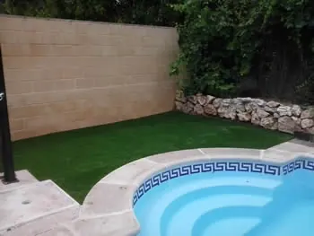 Césped artificial junto a una piscina pequeña